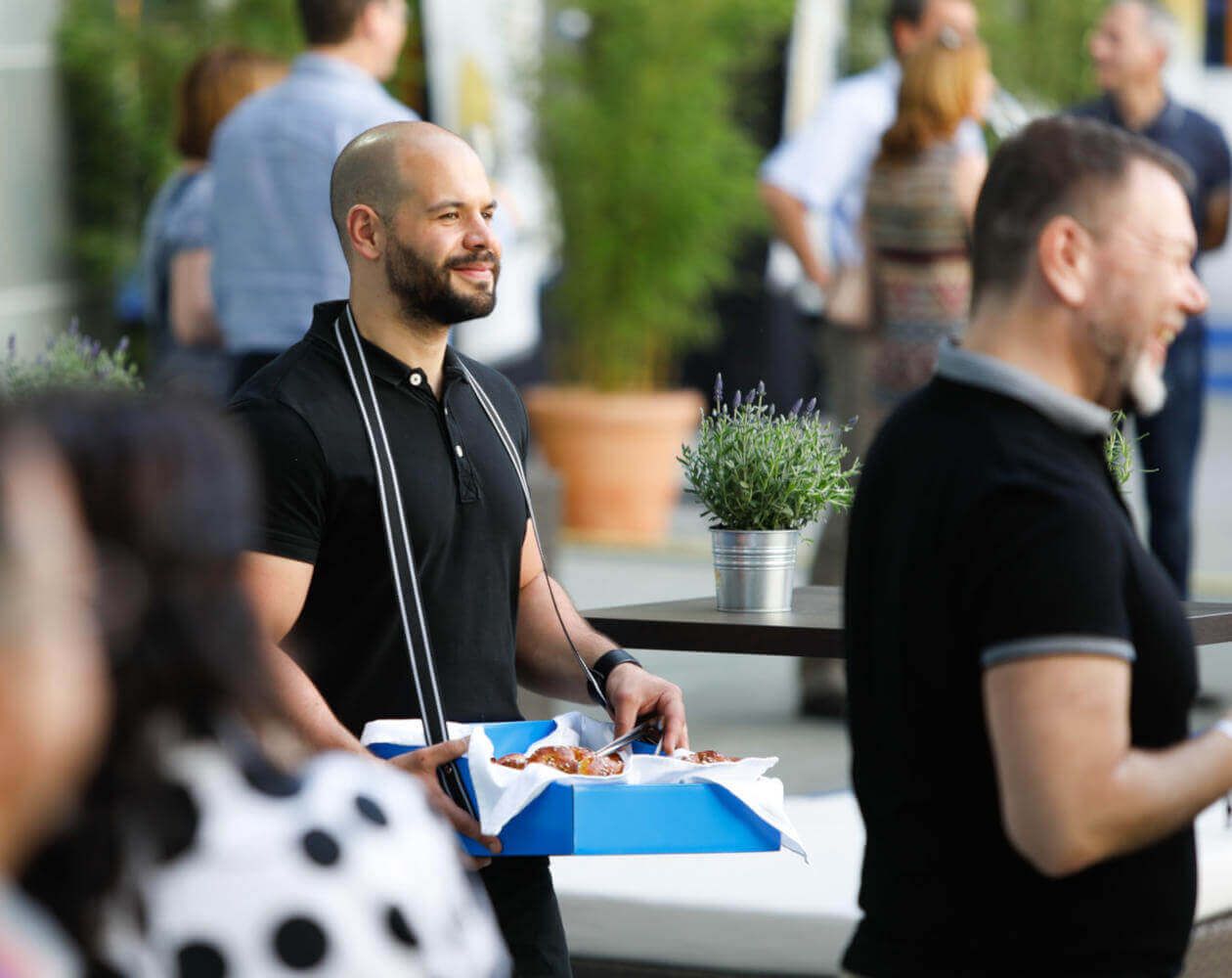 Street-KITCHEN Mitarbeiter bei einem Catering Event verteilt Burger